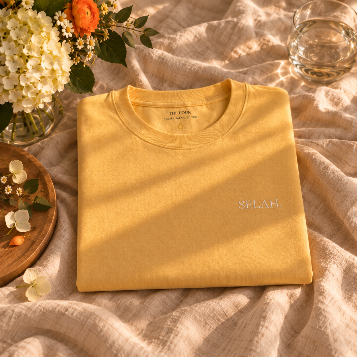 Butter-yellow SELAH tee shirt laid on soft linen